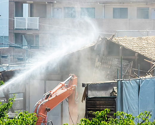 散水を行いながら重機で一般住宅を解体している様子