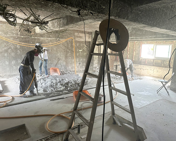 作業員3名が建物の部分的な解体工事を行なっている現場